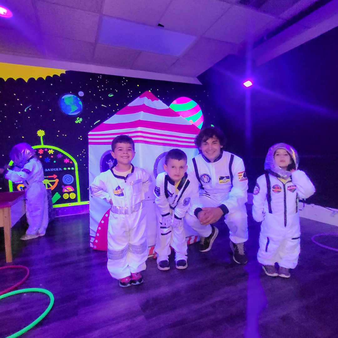 A field trip chaperone with kids playing dress up as astronauts at the museum