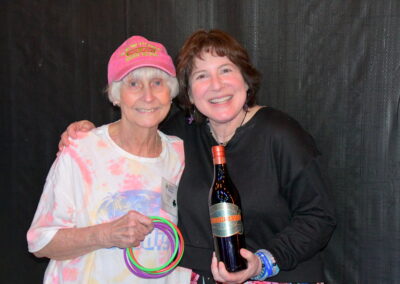 Two womens smiling for the camera holding a bottle of wine