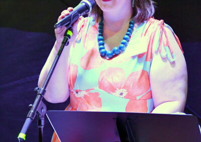 A woman in a flower dress speaking in front of the microphone